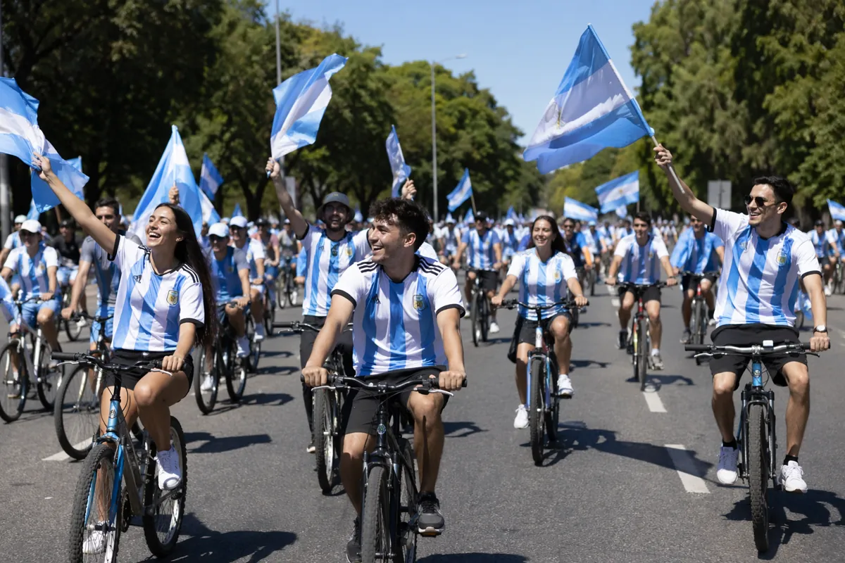 Wide shot of cheerful football fans wearing Argentina national team jerseys riding bicycle